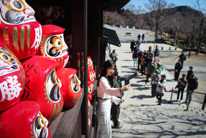 Du khách chụp hình với các búp bê daruma tại Nhật Bản. Ảnh: CNN
