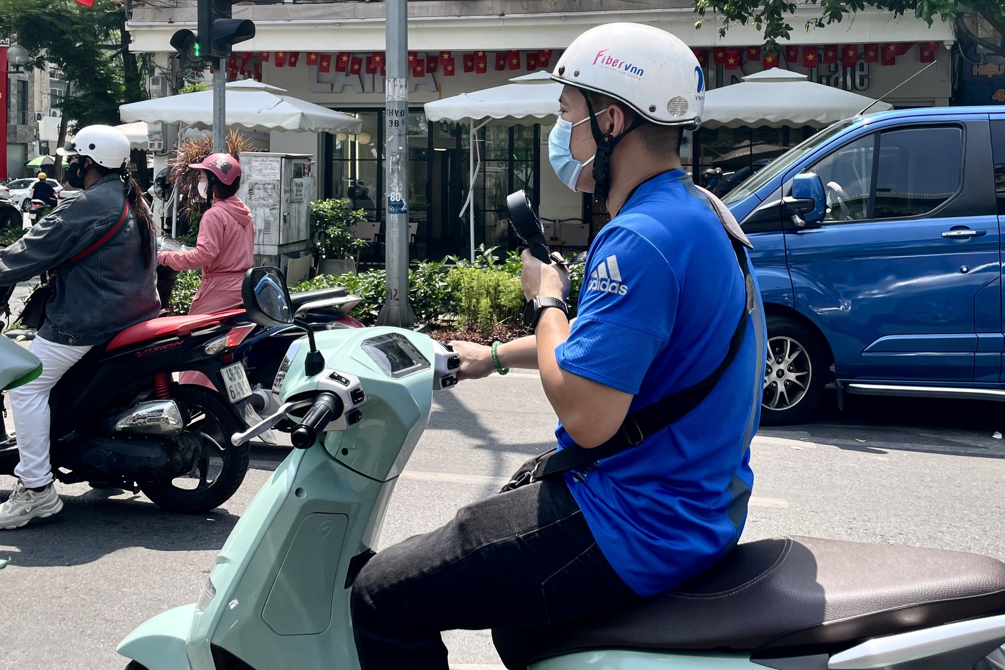 Người đàn ông vừa đi đường vừa dùng quạt tay để đối phó với cái nóng lên đến 36 độ C.