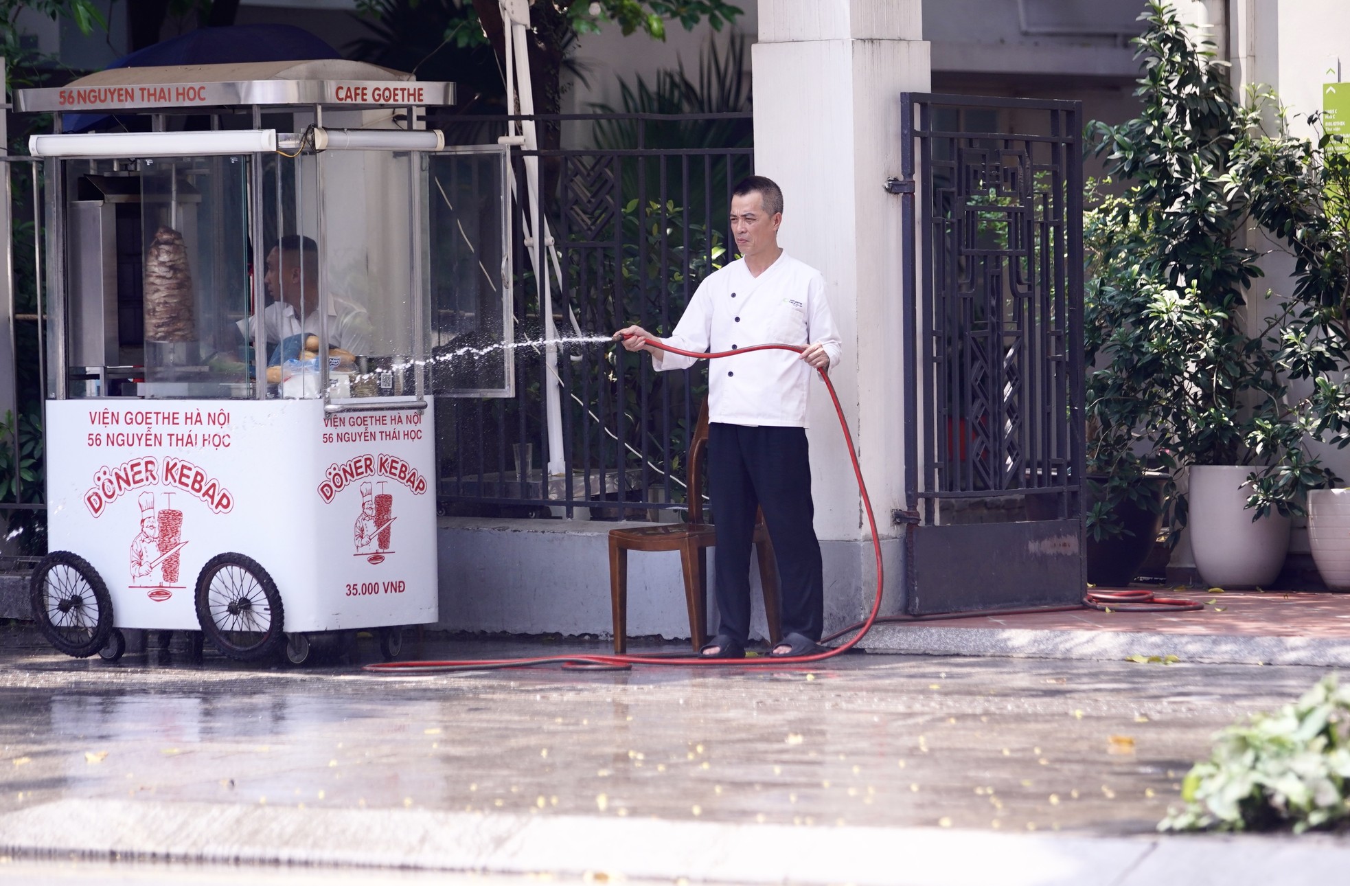 Người đàn ông tưới nước để giảm nhiệt độ vỉa hè.