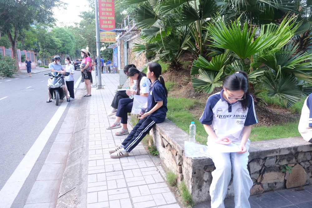 Nhiều thí sinh có mặt từ sớm tại điểm thi, tranh thủ ôn lại bài. Ảnh: TT