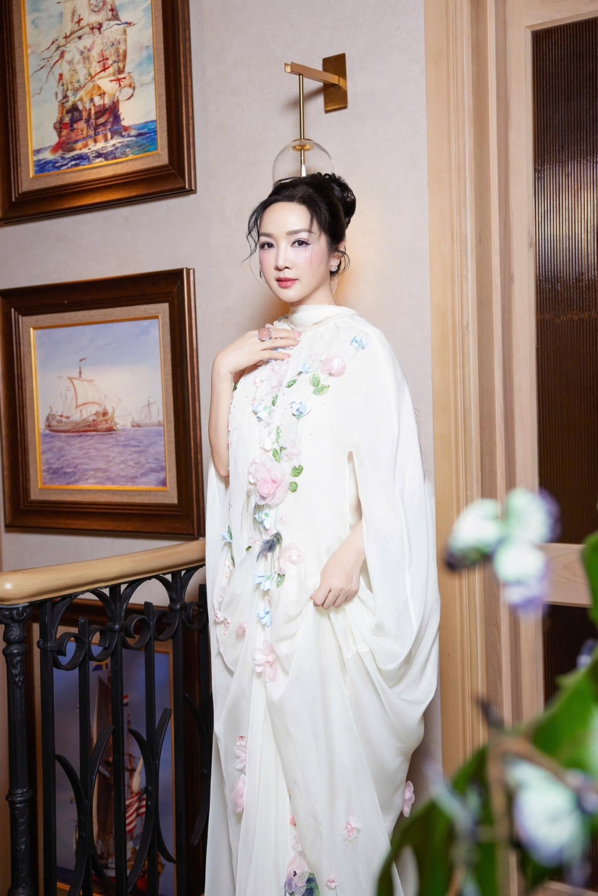 Đầm dáng cape đính hoa đem tới vẻ sang trọng và nữ tính cho Giáng My trong một buổi tiệc. Hoa hậu chọn kiểu tóc búi cao, trang điểm má hồng kẹo ngọt.