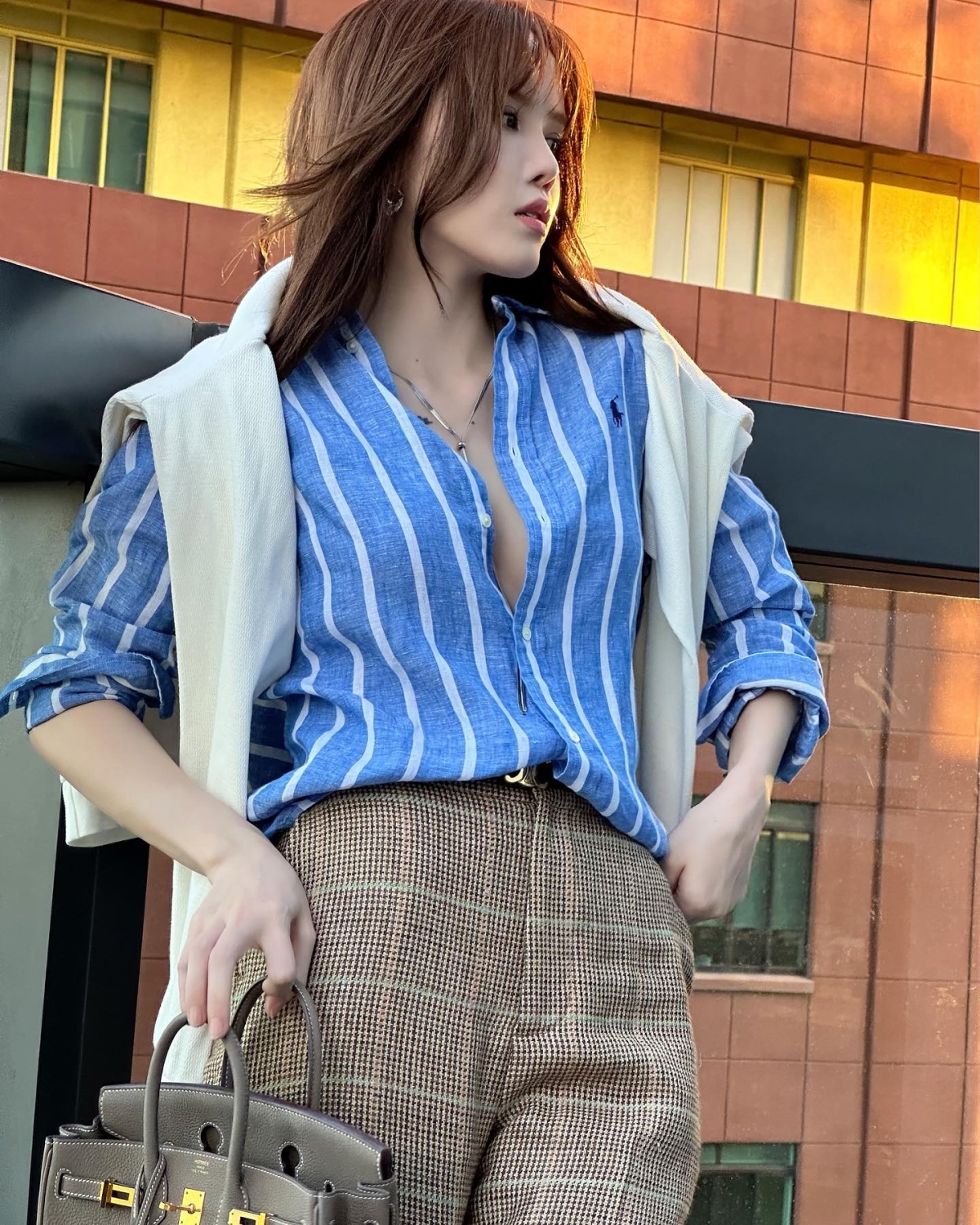 Thiều Bảo Trâm mang đến nét phóng khoáng cho chiếc sơ mi kẻ sọc thêu logo kỵ sĩ. Cô còn kết hợp cùng túi xách giá hơn nửa tỷ đồng, hoàn thiện diện mạo sang chảnh.