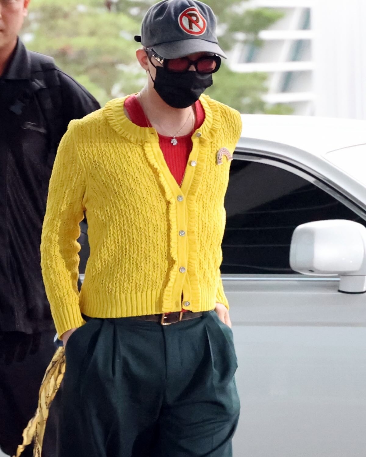 Nghệ sĩ diện chiếc áo cardigan dệt kim màu vàng rực bên ngoài áo ba lỗ đỏ. Thiết kế theo phong cách unisex mà G-Dragon yêu thích và theo đuổi nhiều năm nay.