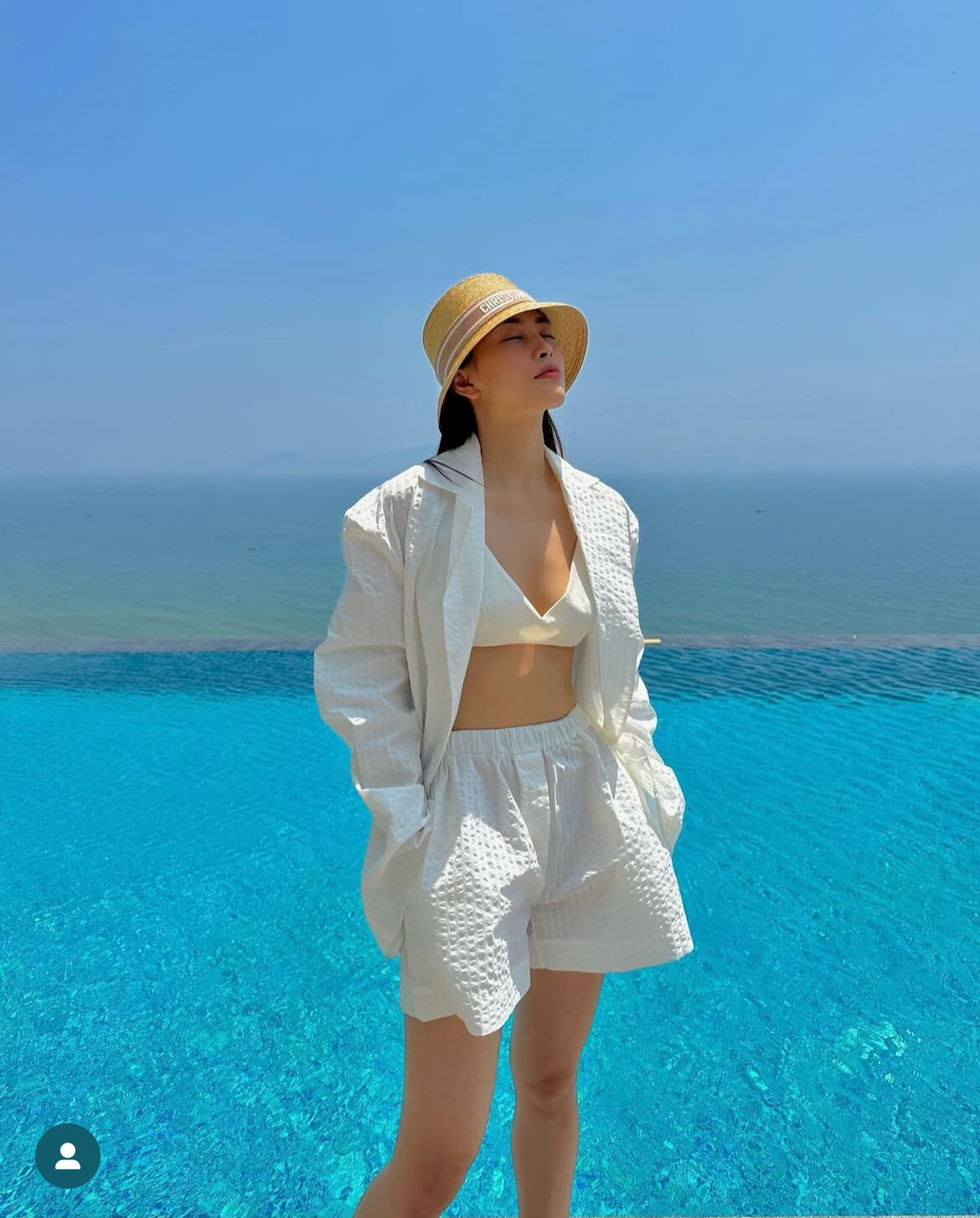 Tiểu Vy cao tay khi phối áo tắm trắng cùng quần short, áo blazer chất liệu cotton mỏng nhẹ, cô mix kèm mắt kính và nón Dior sang chảnh để hoàn thiện tổng thể.