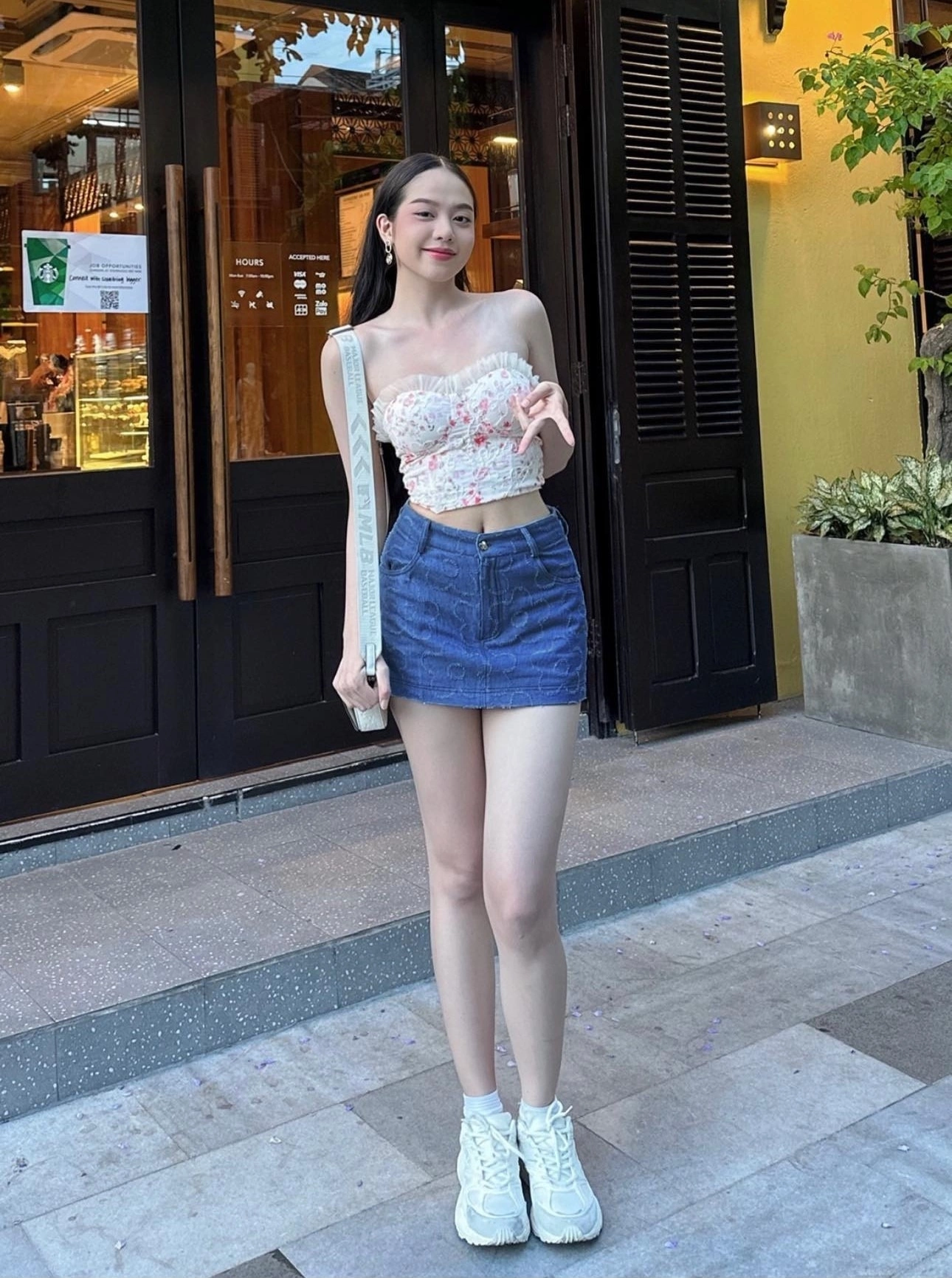 Hoa hậu tôn dáng với chân váy denim ngắn và crop top hoa nhí 450 ngàn đồng cùng chiếc áo cúp ngực khoảng 400 ngàn đồng. Cô phối cùng giày thể thao dưới 2 triệu thường dùng trong những năm gần đây vì rất tiện lợi.