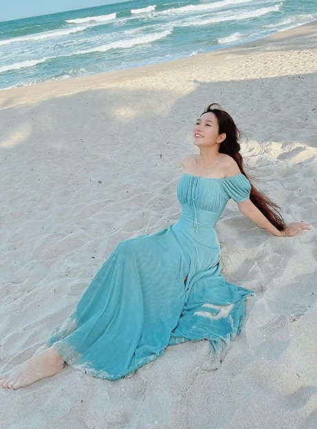 Đầm liền với những khoảng hở nhẹ nhàng như trễ vai, xẻ đùi... tôn đường cong quyến rũ của bà mẹ bốn con. Váy maxi phù hợp với không gian biển xanh, nắng vàng, đồng thời giúp Minh Hà tôn vóc dáng mảnh mai, chiều cao 1,63 m.