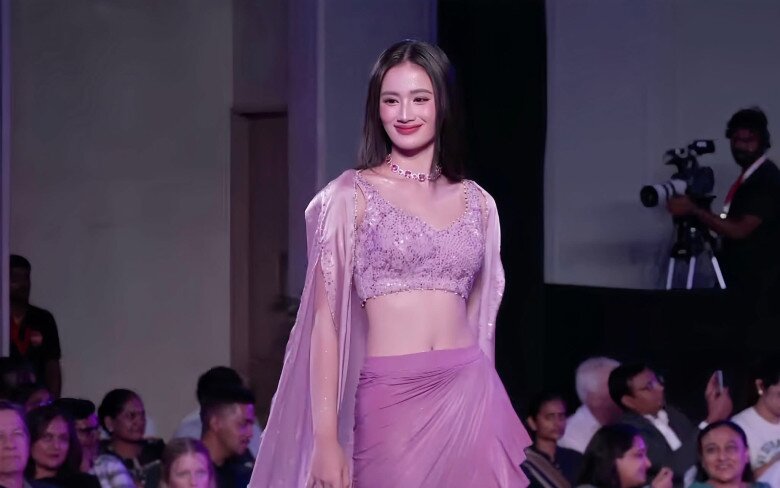 Ở phần trình diễn đầu tiên, Hoa hậu Ý Nhi diện trang phục tím nhạt, cách điệu tinh tế từ trang phục truyền thống Ấn Độ. Đây là sáng tạo của nhà thiết kế người Ấn Archana Kochhar. Trang phục được dệt thủ công với kiểu dáng áo croptop và chân váy giúp Ý Nhi khoe đường cong, vòng eo nhỏ. 