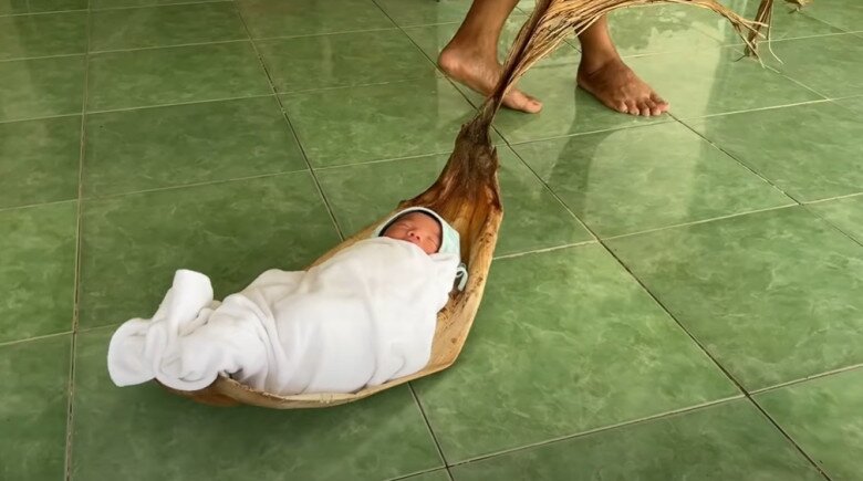 Em bé được ông ngoại đặt vào mo cau để kéo.