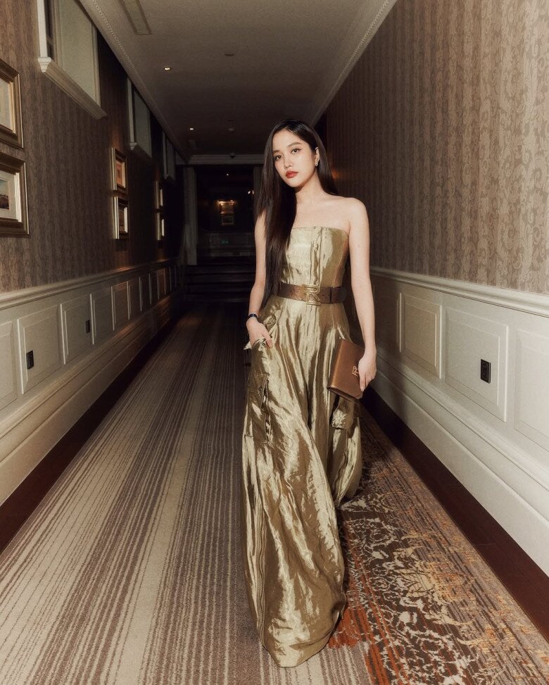 Ngay sau đó, cô chuyển sang vẻ thanh lịch với chiếc đầm dạ hội ánh kim vàng ánh từ Ralph Lauren, nhấn bằng thắt lưng kim loại bản lớn và clutch đồng điệu. 