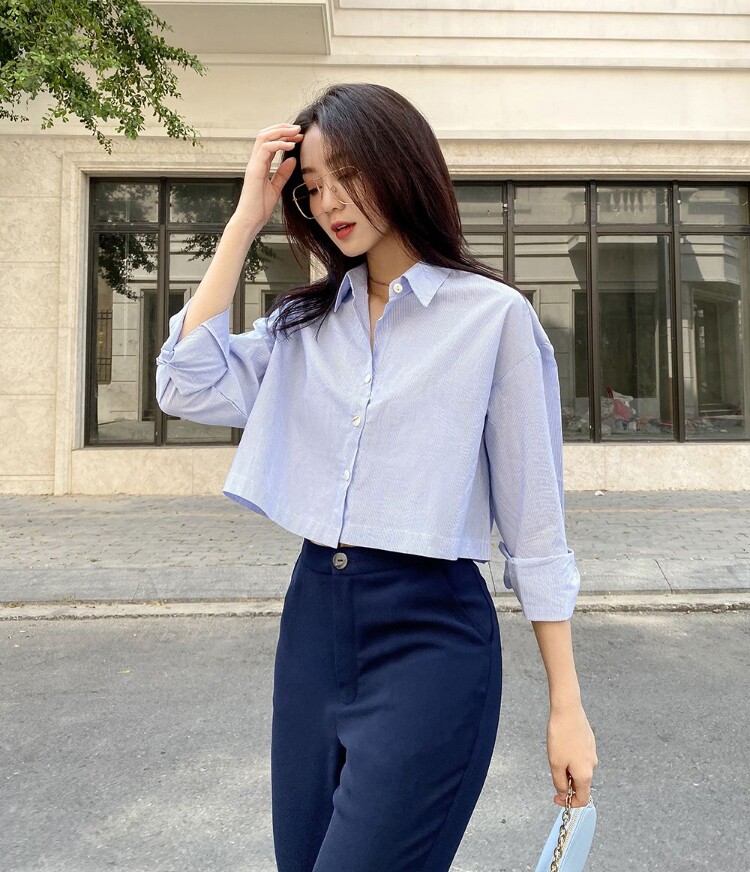 Sơ mi croptop xanh pastel phối khéo léo với quần tây cạp cao tạo nên tổng thể hài hòa theo tỷ lệ vàng trên ngắn – dưới dài. 