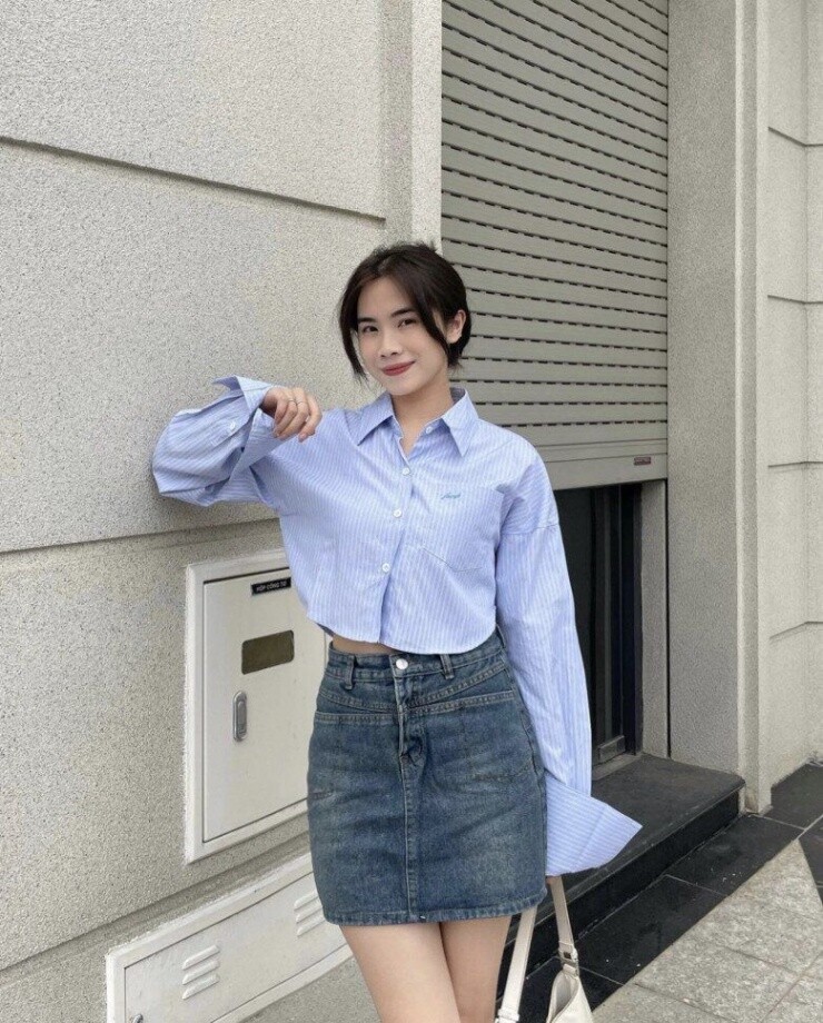Sự tương phản thú vị giữa áo sơ mi sọc oversized cá tính và chân váy denim mini mang đến vẻ ngoài trẻ trung, năng động.