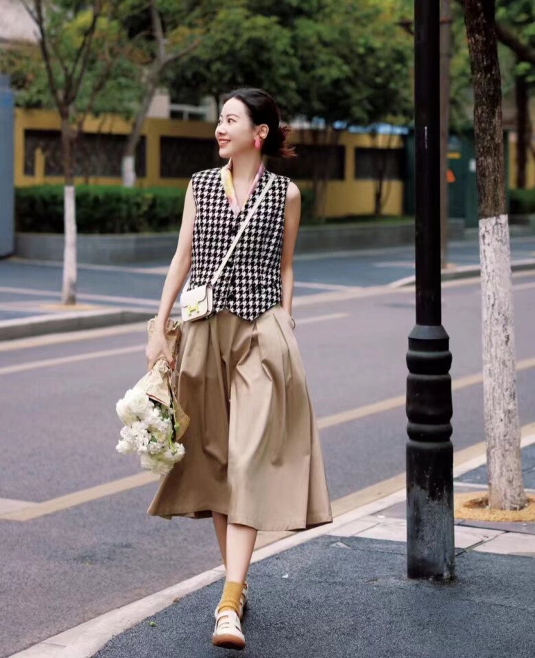 Gile họa tiết houndstooth nổi bật, mix cùng chân váy midi màu beige xếp ly nhẹ góp phần tạo nên diện mạo retro.