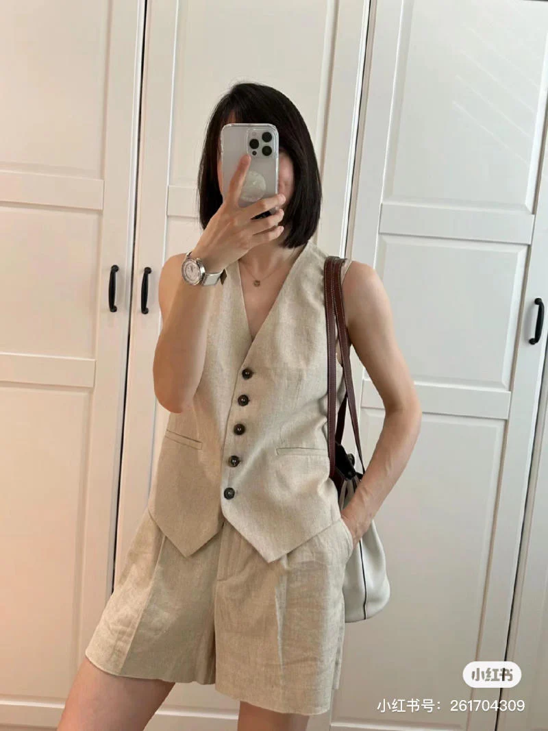 Bộ gile và quần short linen tông beige mang đến hình ảnh thanh lịch, nhẹ nhàng nhưng vẫn phóng khoáng. Thiết kế cổ chữ V và hàng cúc tối màu tạo nên sự cân đối giữa nét cổ điển và hiện đại.