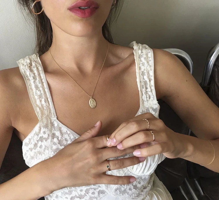 Một khoảnh khắc gợi cảm được tạc nên từ chất liệu ánh kim: sợi dây chuyền vàng mảnh mai với mặt đồng xu cổ điển, vòng tay tinh tế và những chiếc nhẫn nhỏ xếp tầng khéo léo trên đôi tay.