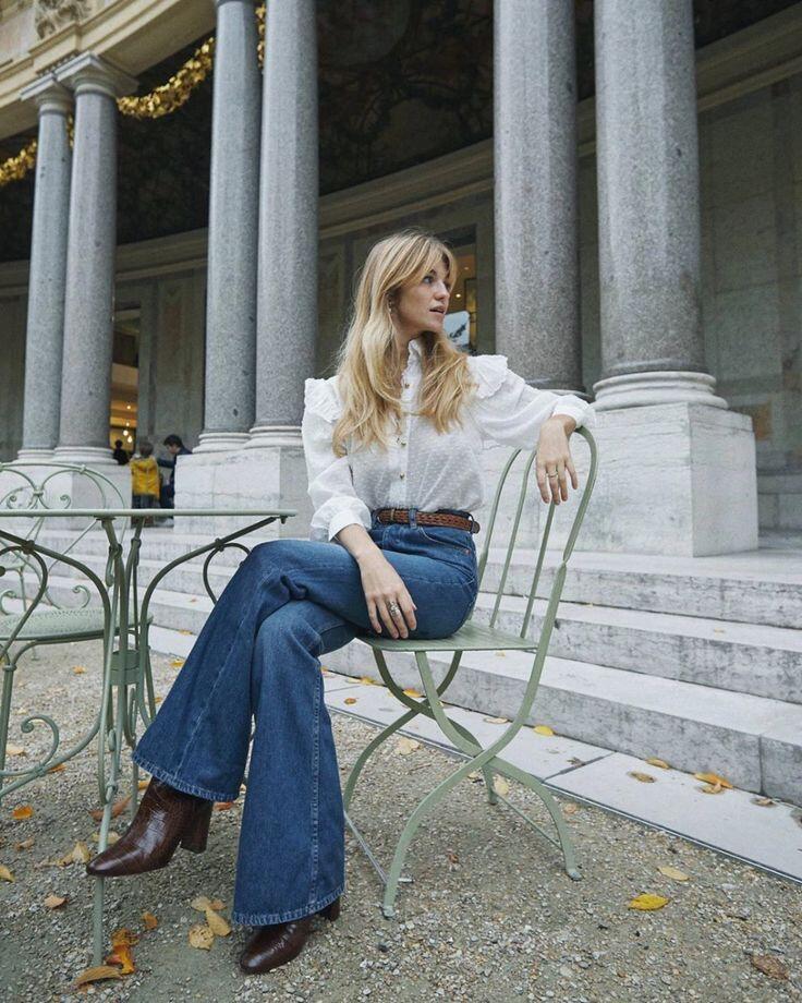 Áo blouse trắng họa tiết subtle kết hợp jeans ống loe xanh denim tạo nên bảng màu hài hòa, sang trọng.