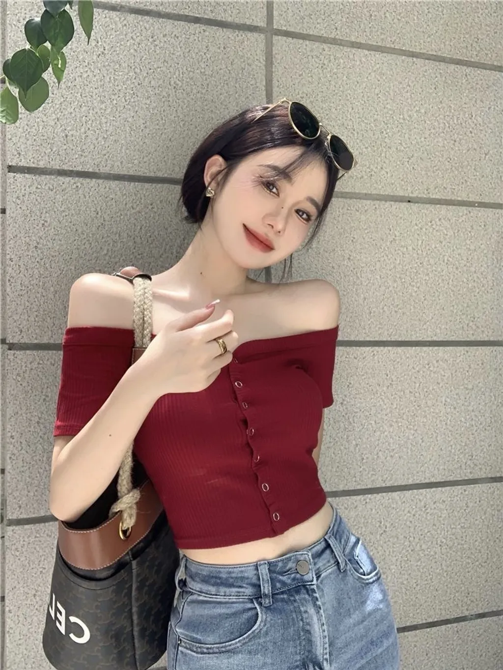 Áo trễ vai ôm sát màu đỏ rượu vang phối cùng quần jeans tạo nên diện mạo quyến rũ mà cá tính. 