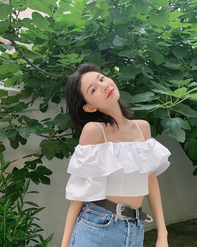 Áo crop top trễ vai phối bèo tầng giúp khoe trọn bờ vai mềm mại và vòng eo thon gọn.