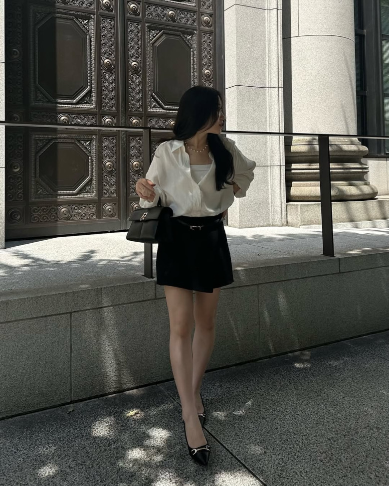 Nàng blogger Hyorori, dù chỉ cao 1,51m vẫn có thể lên đồ cực đỉnh và trông như cao 1,6m nhờ phối áo sơ mi trắng oversized cùng chân váy đen chữ A – combo kinh điển giúp tạo hiệu ứng đôi chân dài miên man.