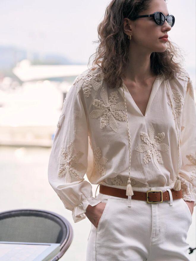 Áo sơ mi thêu hoa bản to phối cùng quần jeans trắng mang đến phong cách thanh lịch và nhẹ nhàng. 