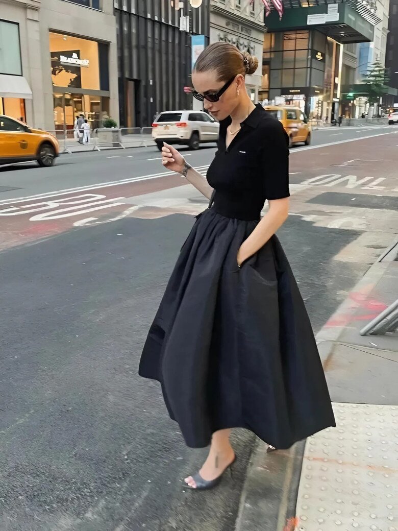 Áo polo đen ôm sát kết hợp chân váy xòe dài chất liệu taffeta, tạo nên diện mạo tinh tế và quyền lực.