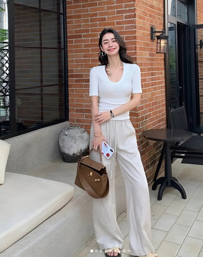 Vẻ thanh lịch hiện đại được thể hiện qua áo thun cổ sâu cùng quần lanh ống suông màu beige.