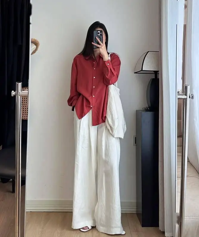 Sơ mi đỏ rượu vang mix cùng quần ống rộng màu trắng mang đến diện mạo phóng khoáng nhưng không kém phần cuốn hút.