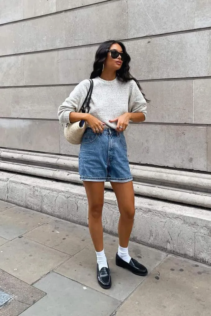Nét cổ điển pha hiện đại với áo len mỏng, quần short jean và giày loafer da đen. Tất trắng nhấn mạnh sự tinh tế, tạo điểm cân bằng giữa sự thoải mái và thanh lịch.