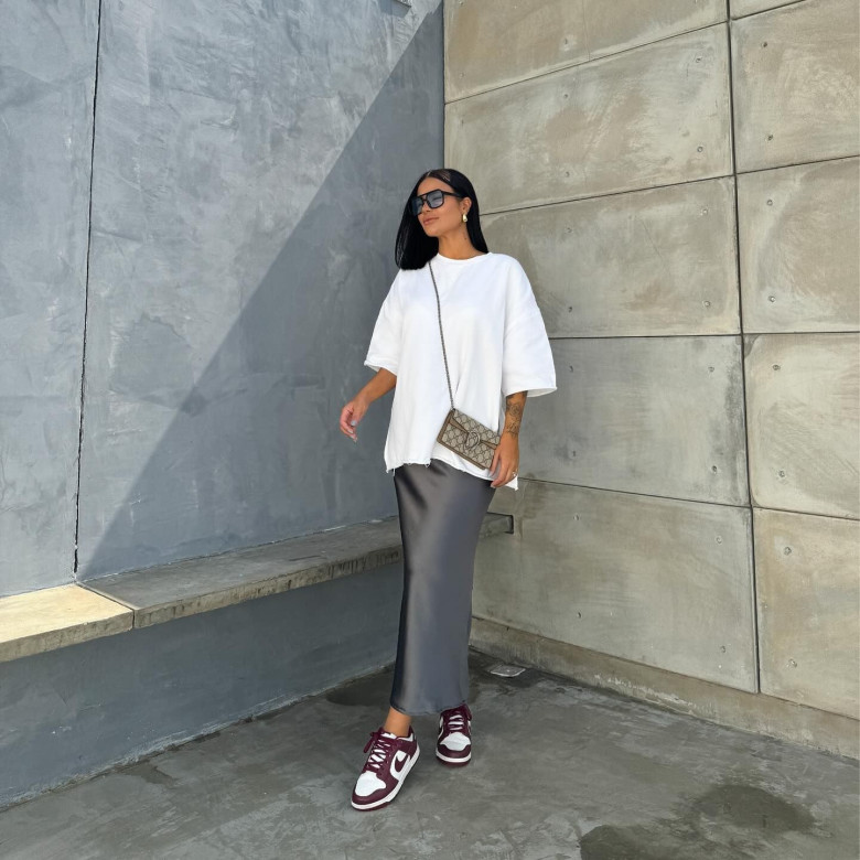 Váy satin xám dáng ôm là tuyên ngôn của sự quyến rũ tối giản, kết hợp cùng áo oversized trắng và sneaker đỏ rượu, mang đến vẻ ngoài cá tính mà vẫn giữ được nét nữ tính.