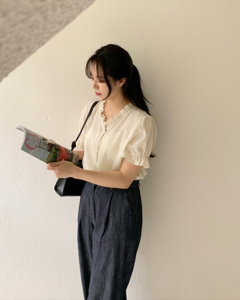 Áo blouse tay bồng nhẹ với hàng khuy nhỏ xinh được phối cùng quần vải linen xám than, tạo nên outfit nhẹ nhàng mà không kém phần chỉn chu.