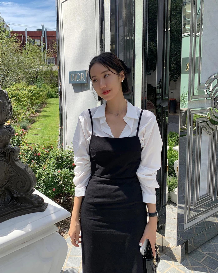 Sự kết hợp cổ điển giữa đầm hai dây đen và sơ mi trắng mang đến vẻ thanh lịch, hiện đại. Lối phối layer này gợi cảm giác tinh tế, thích hợp cho những buổi gặp gỡ tại các địa điểm sang trọng.