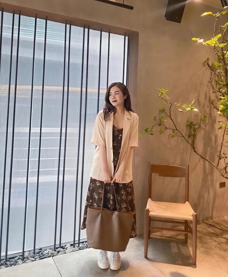 Chiếc đầm hoa nhí dịu dàng được cân bằng hoàn hảo với blazer màu be và túi tote cỡ lớn, tạo nên tổng thể đậm chất vintage Hàn Quốc.