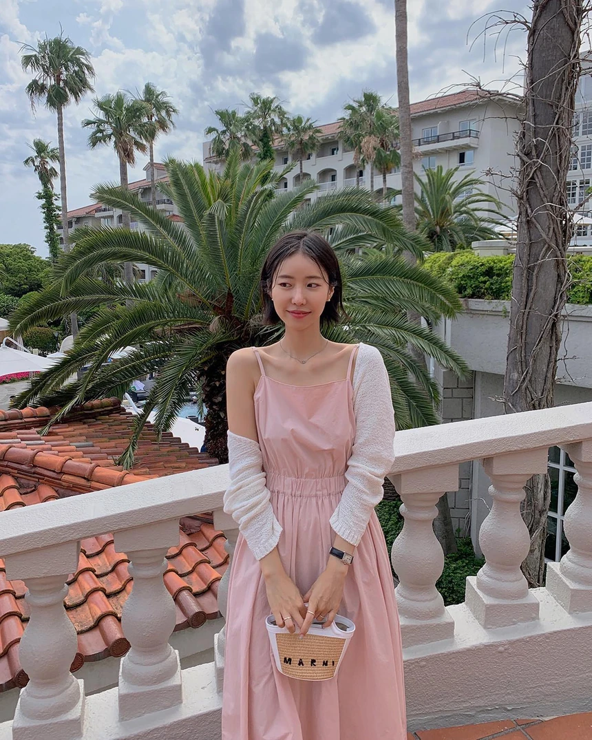 Áo dệt kim mỏng dài tay phối cùng váy 2 dây hồng pastel giúp chị em ngọt ngào hơn lại có thể chống nắng khi đi biển.