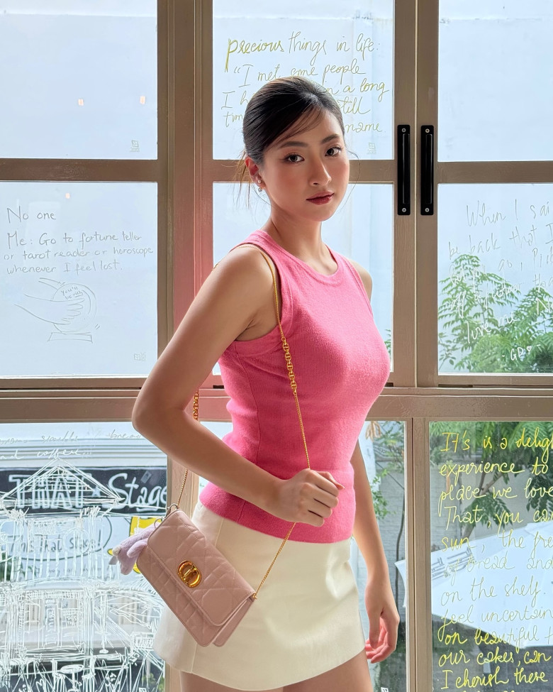 Nàng hậu xinh đẹp tỏa sáng trong áo len tăm sát nách màu hồng rực, kết hợp chân váy mini trắng kem. Túi đeo vai ton-sur-ton càng tôn lên vẻ sang chảnh, trẻ trung.