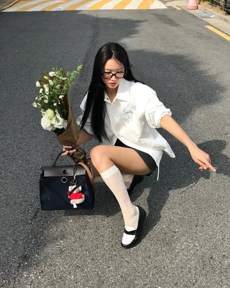 Áo sơ mi oversized trắng kết hợp với chân váy ngắn và tất cao cổ trắng là công thức kinh điển của phong cách preppy.