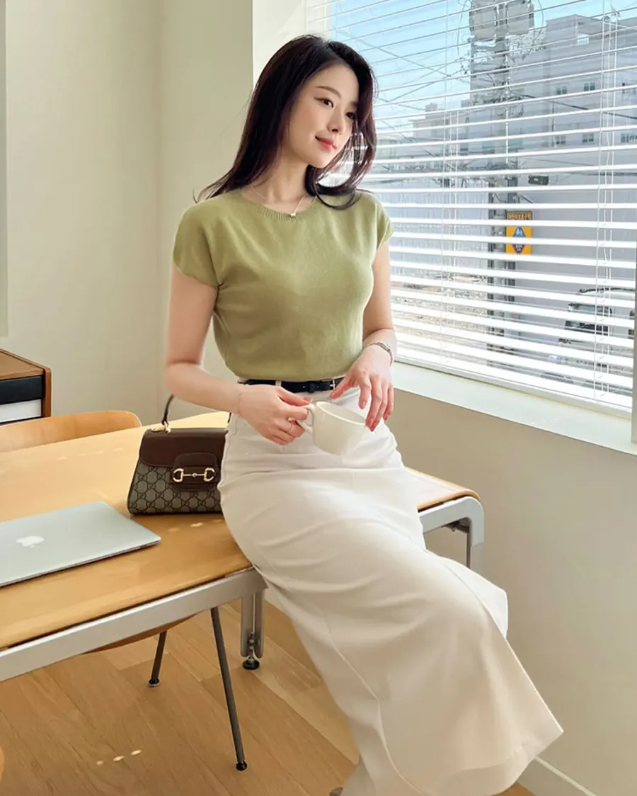 Sự kết hợp giữa áo phông mỏng màu olive và chân váy trắng tạo cảm giác tinh tế, nhã nhặn. Phong cách này vừa đủ nữ tính, vừa mang hơi hướng công sở hiện đại, lý tưởng cho những buổi café cuối tuần.