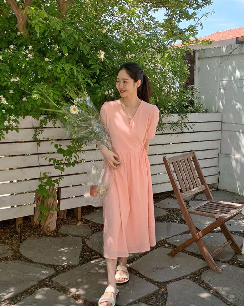 Chiếc váy quấn dáng midi với điểm nhấn eo nhẹ nhàng giúp tạo hiệu ứng “thắt eo”, khéo léo che bụng và làm dáng thanh thoát hơn. Chất liệu mềm rũ cùng tông màu ngọt ngào còn giúp gương mặt trông sáng và trẻ trung hơn.