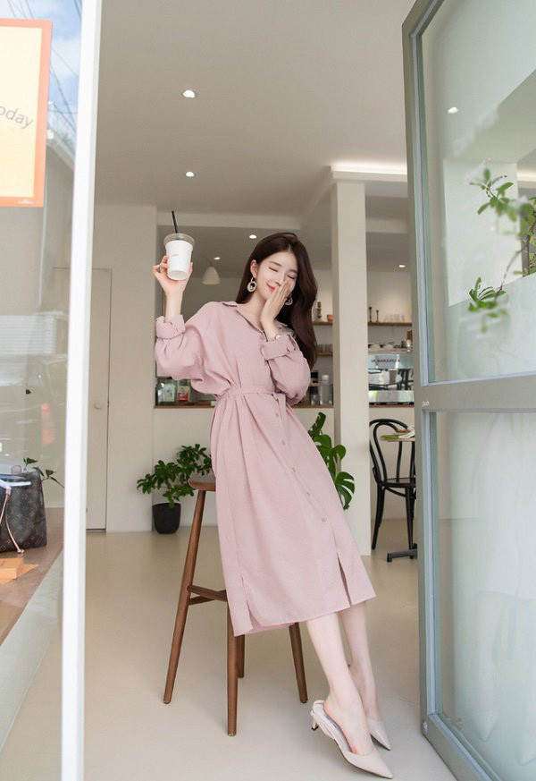 Váy sơ mi liền thân tông hồng phấn kết hợp thắt lưng tôn vòng eo, đồng thời che bắp tay to nhờ tay bồng tinh tế. Kiểu dáng suông nhẹ, cài khuy dọc còn giúp kéo dài cơ thể, tạo vẻ cao ráo và thanh lịch cho người mặc.