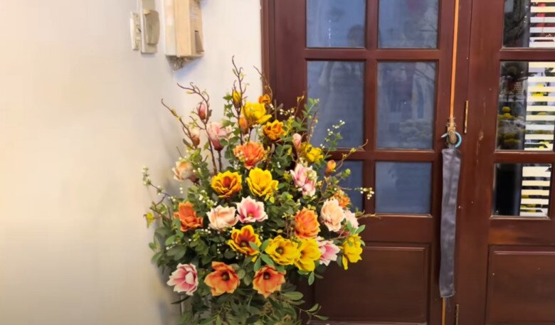 Góc cửa gỗ kính đơn giản được tô điểm bằng bình hoa nhiều màu sắc do fan tặng. Cách bài trí nhẹ nhàng nhưng không kém phần sinh động.