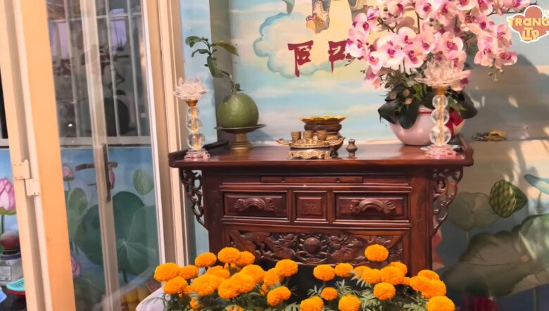 Bàn thờ Tổ nghiệp được chạm khắc tinh tế, đặt đối diện bức tường vẽ tay sinh động. Mỗi vật phẩm thờ cúng đều được sắp xếp ngay ngắn. Hoa cúng tươi tắn và đầy sắc màu.