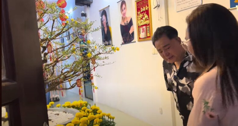 Vào hồi đầu năm, không gian phòng khách nhà ông rực rỡ sắc xuân với cành mai lớn trang trí lộc đỏ. Trên tường treo nhiều ảnh kỷ niệm của gia đình và đồng nghiệp. Góc phòng tạo cảm giác ấm cúng và truyền thống.