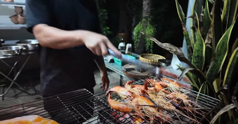 Tôm sú được nướng trên vỉ riêng để đảm bảo chín đều và giữ được vị ngọt tự nhiên. Anh cho biết: “Mình chia hai bếp, một bên nướng tôm, bên kia nướng cá và mực”.