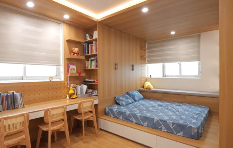 Phòng ngủ của các con nam nghệ sĩ thiết kế hiện đại với giường bục tích hợp hộc kéo, bàn học dài ba chỗ và kệ sách tiện nghi.