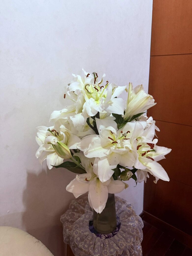 Hoa ly trắng được cắm đơn sắc trong một bình cao, đặt ở góc phòng – kiểu cắm đứng truyền thống, phù hợp với không gian gọn gàng, thanh lịch.