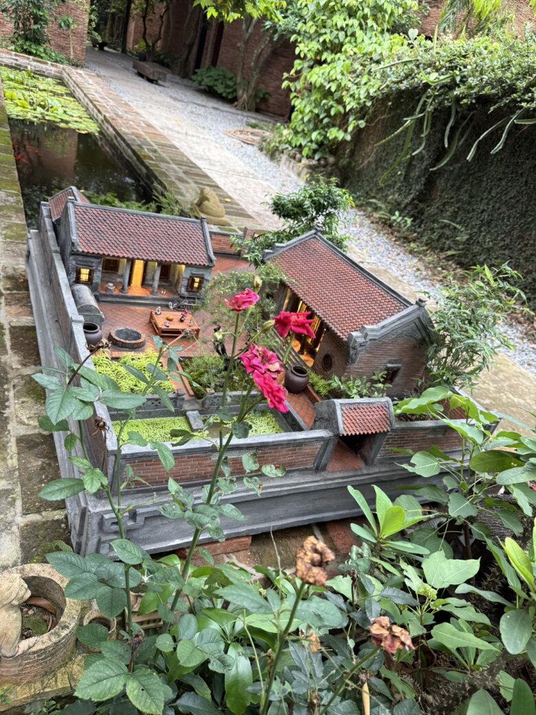 Một góc nhìn khác của mô hình cho thấy lối đi lát gạch, ao thả bèo và vườn cây xanh mát. Các chi tiết như chum nước, giếng gạch cũng được tái hiện đầy sinh động.