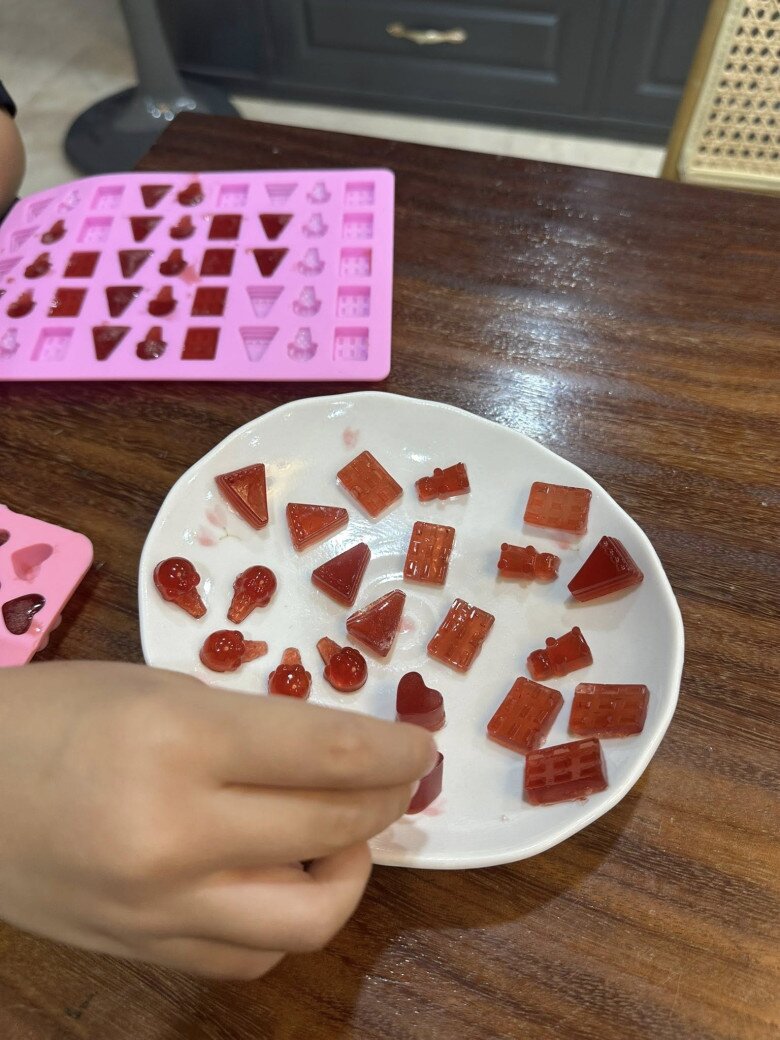 Cận cảnh một đĩa kẹo với đủ hình dạng ngộ nghĩnh: Trái tim, viên gạch, cây kem… màu đỏ rực rỡ và độ dẻo bóng mịn chẳng kém gì kẹo mua ngoài tiệm.