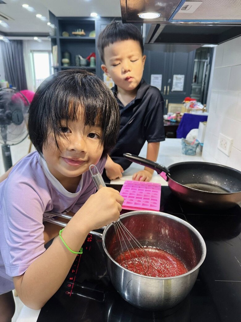 Hai nhóc tì Bơ - Ruốc đang khuấy nồi siro đỏ au. Đây là bước đun hỗn hợp gelatin và nước trái cây, một công đoạn quan trọng để kẹo dẻo được chuẩn vị.