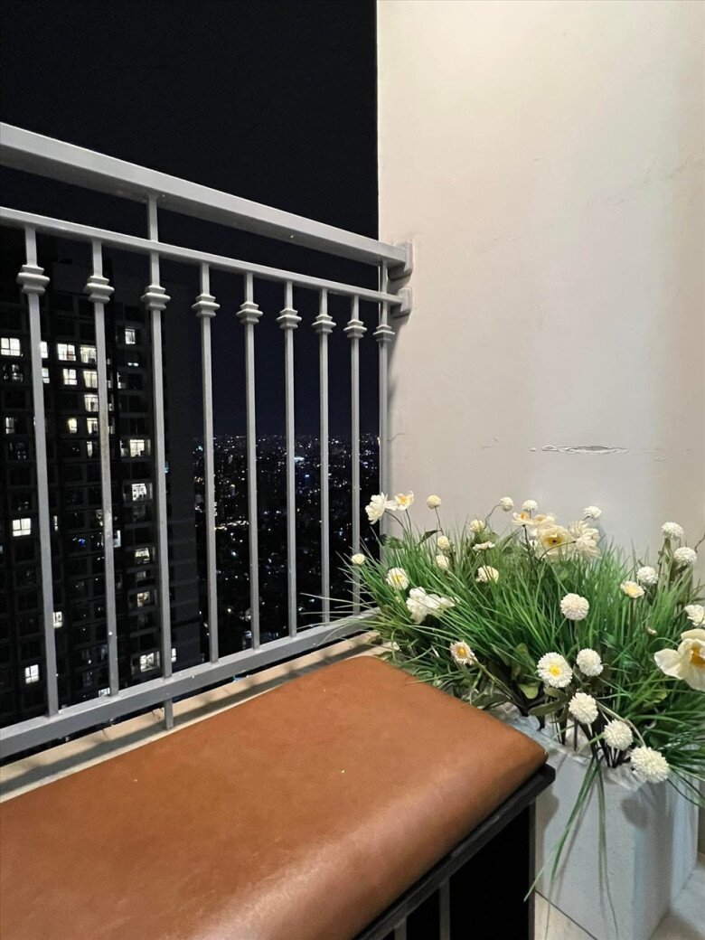Ban công nhỏ nhưng thoáng mát, với băng ghế nệm và chậu cây hoa tạo thành góc thư giãn lý tưởng vào ban đêm.