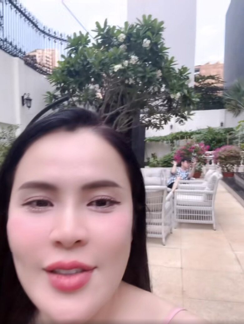 Cô cũng lia máy đến một góc sân nơi ông xã Vũ Luân đang ngồi thư giãn. Nơi đây được bài trí bàn ghế mây trắng dưới tán cây sứ. Cảnh vật hài hòa, xen giữa cây cối và nội thất ngoài trời.
