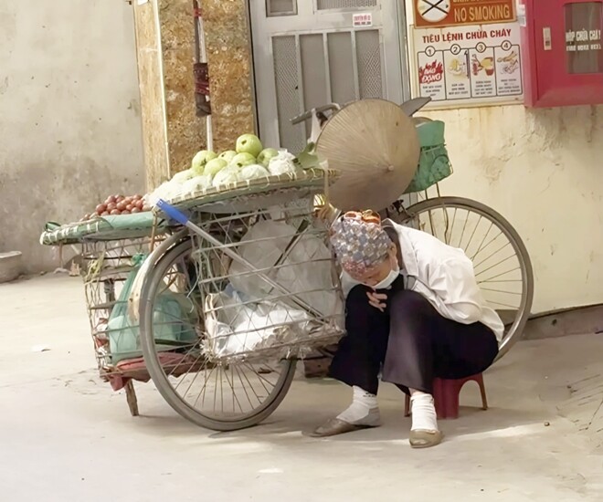 Giấc ngủ trưa vội vã bên đường của cô bán hoa quả dạo