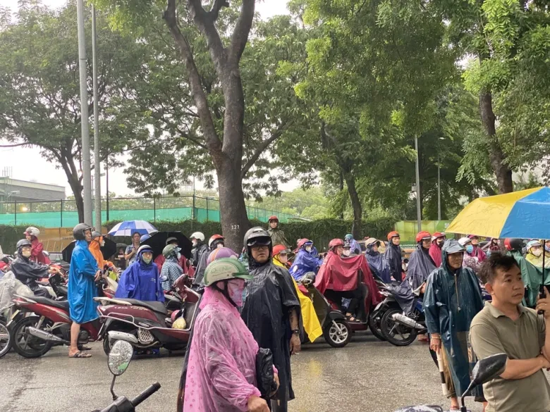 Phụ huynh xếp hàng dài trước điểm thi chờ con trong mưa 